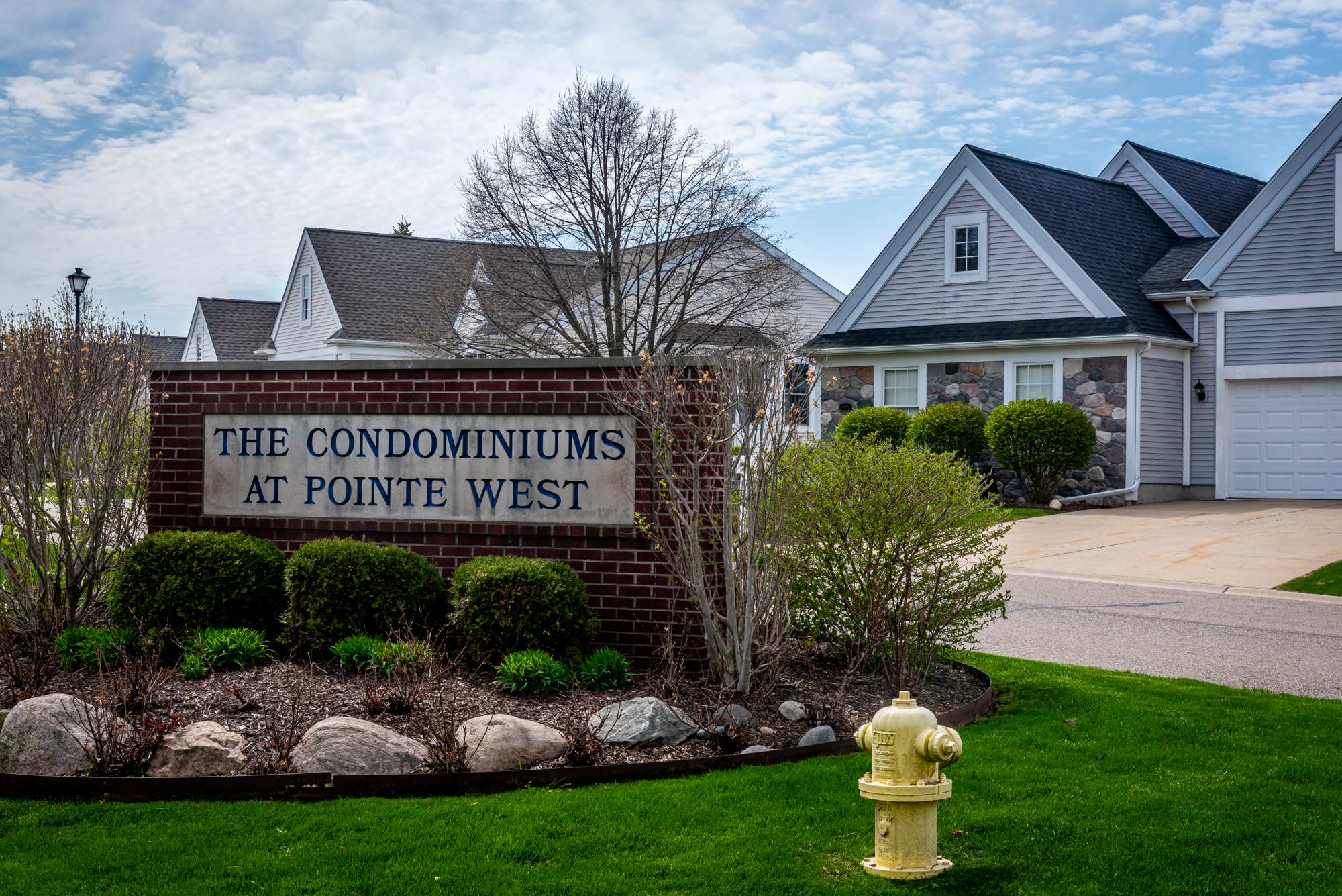 The Condominiums of Pointe West sign in a small garden